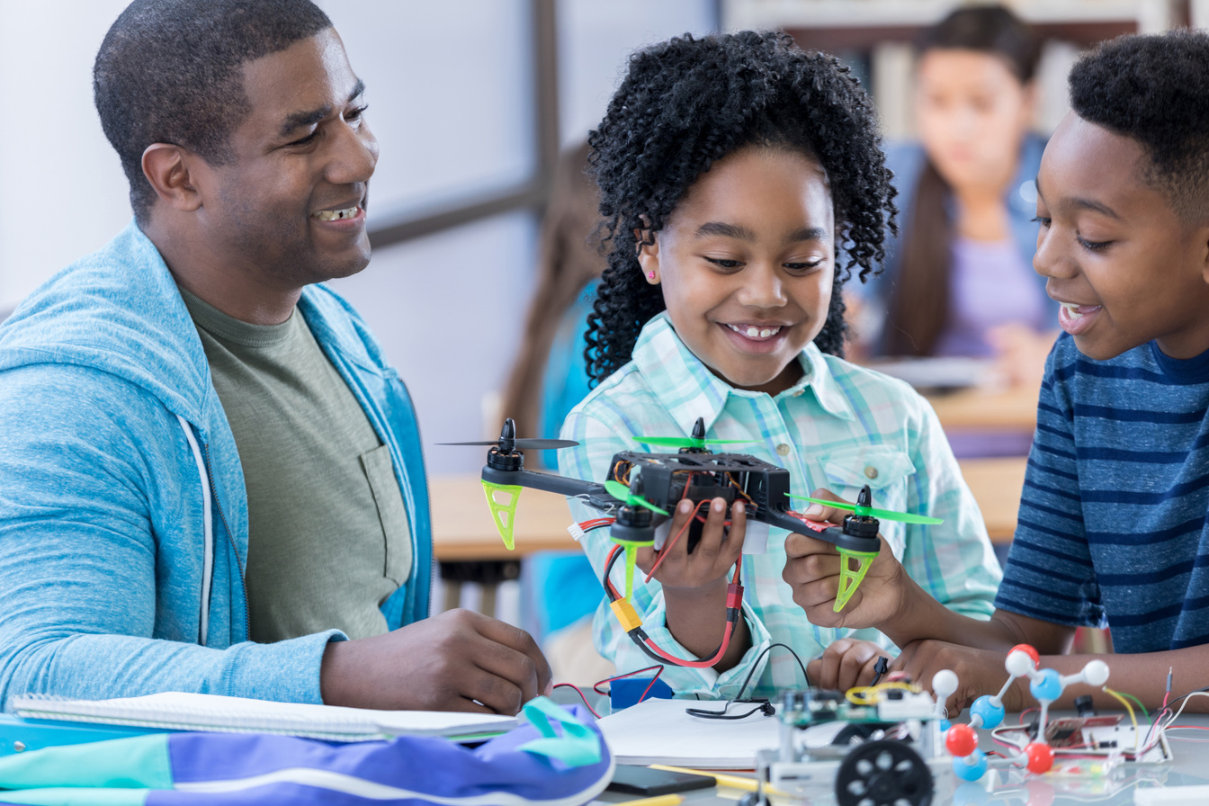 Cheerful STEM middle school students build drone