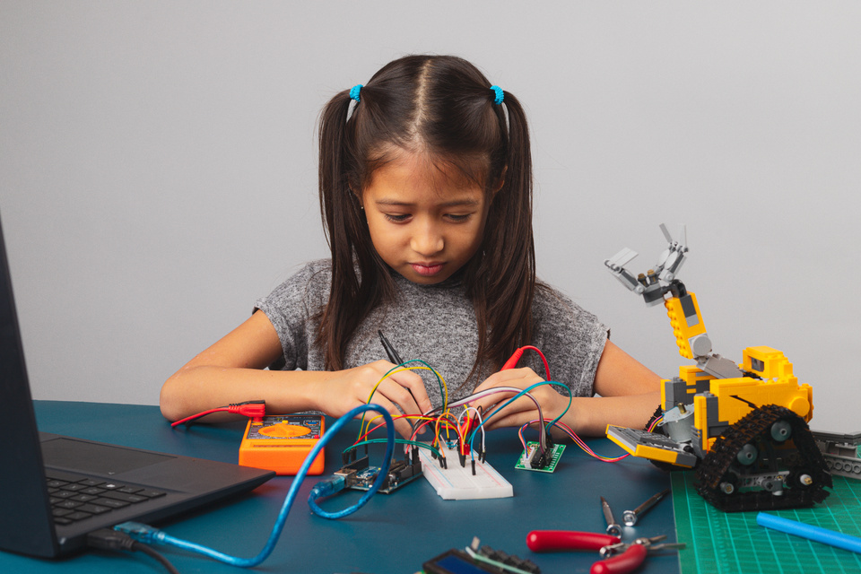 Kid Repairing Something with Wires and Laptop